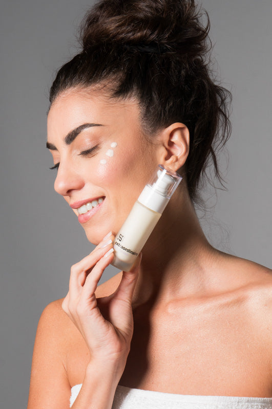 Giovane donna che applica un prodotto Sensitiva alla pelle, mostrando il packaging della linea skincare al CBD  anti age per una pelle idratata e luminosa